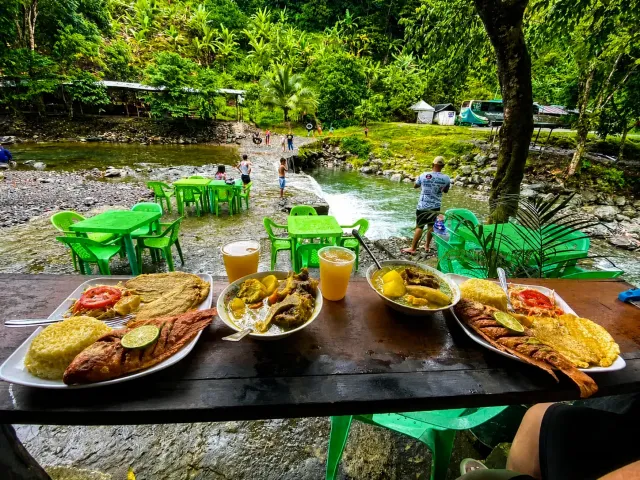 Platos de comida servidos frente al entorno natural y río de Piedras Blancas.